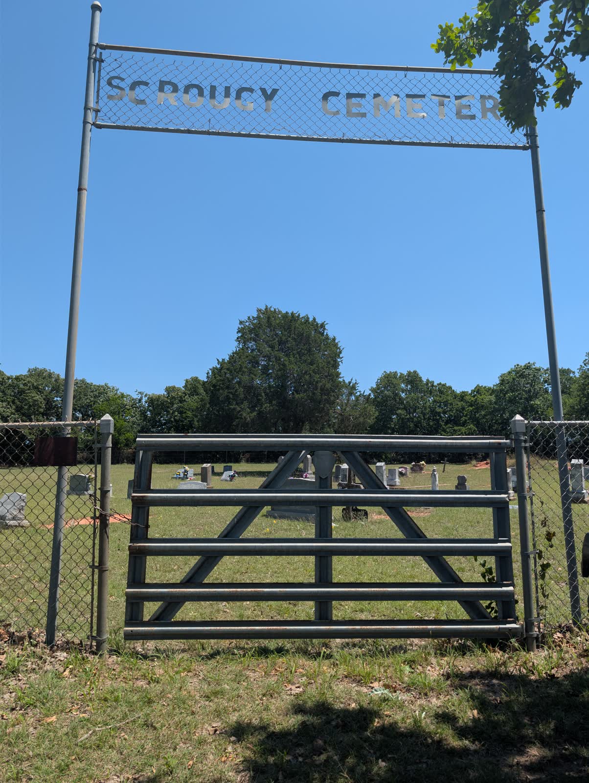 The chain-link banner sign and pipe gate at the entrance to Scrougy Cemetery (Prospect Cemetery), rural Montague County, Texas