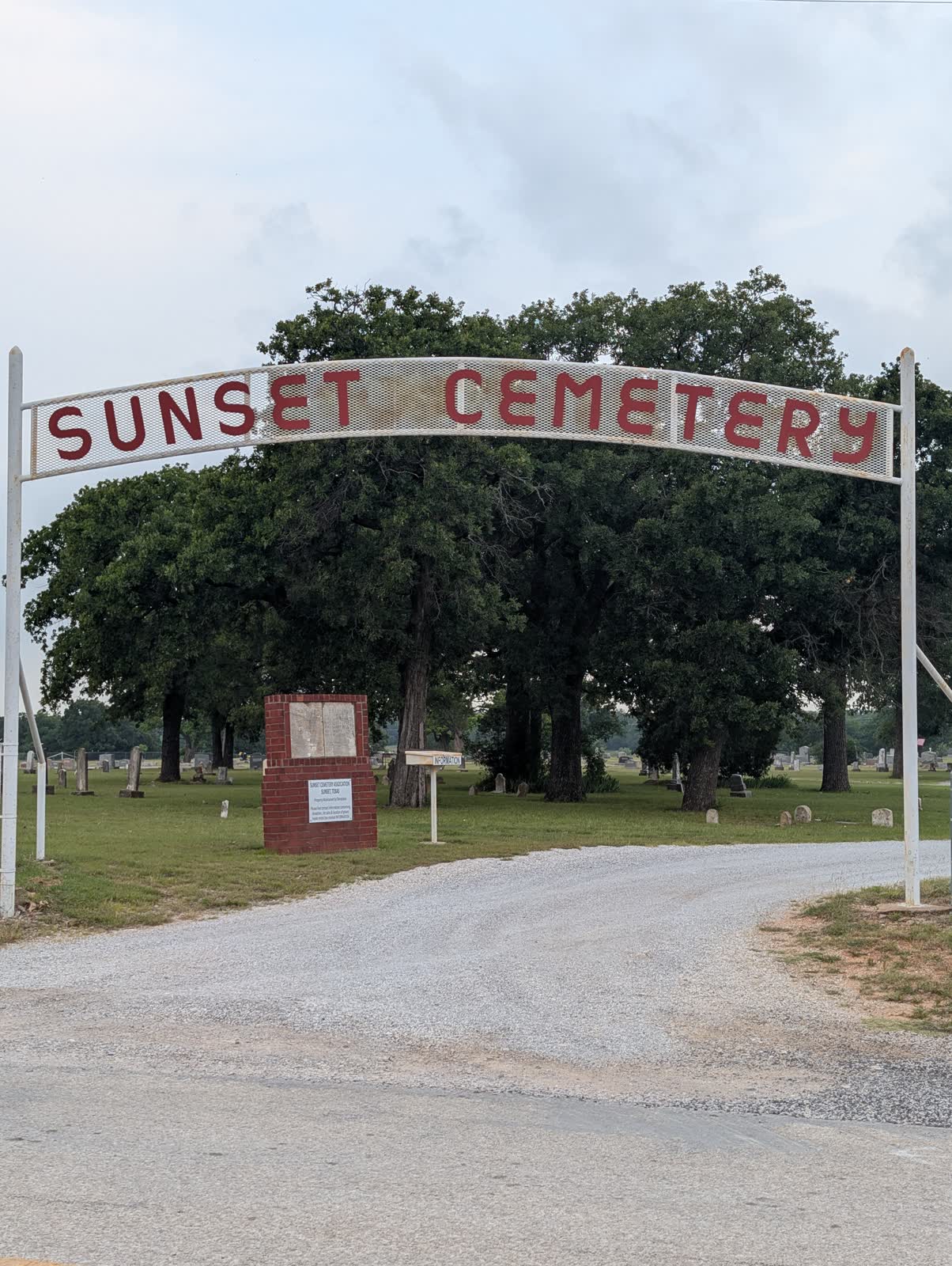 The white entrance arch of Sunset Cemetery in Sunset, Texas, with the Sunset Cemetery Association marker beneath it
